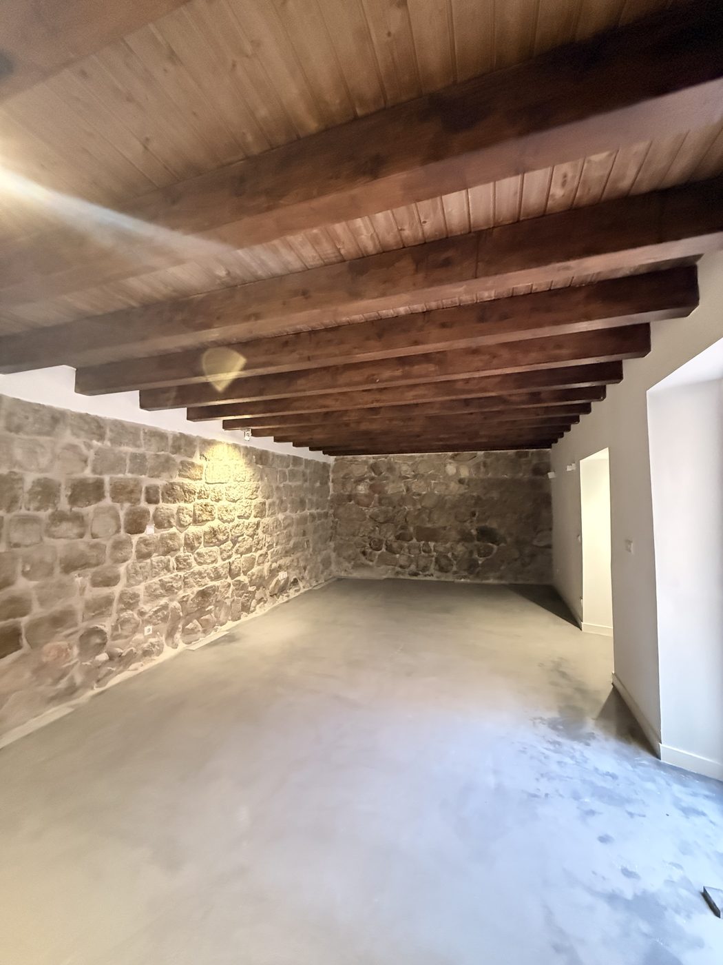 Salón con paredes de piedra y vigas de madera restauradas